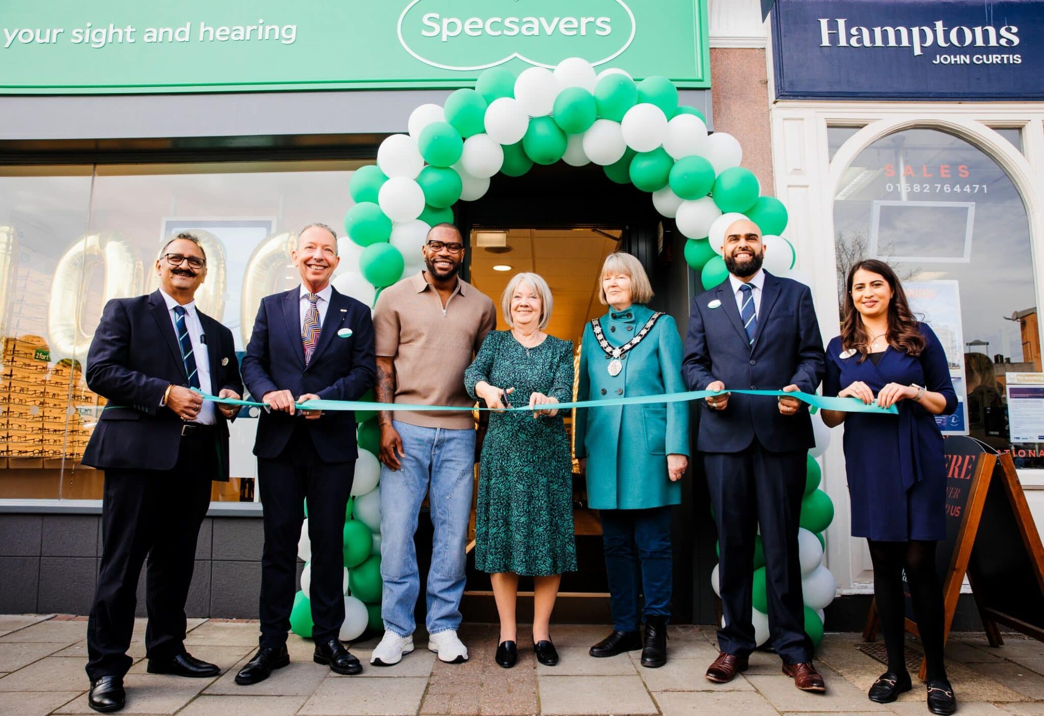 Group of adults cutting ribbon to new Specsavers practice.